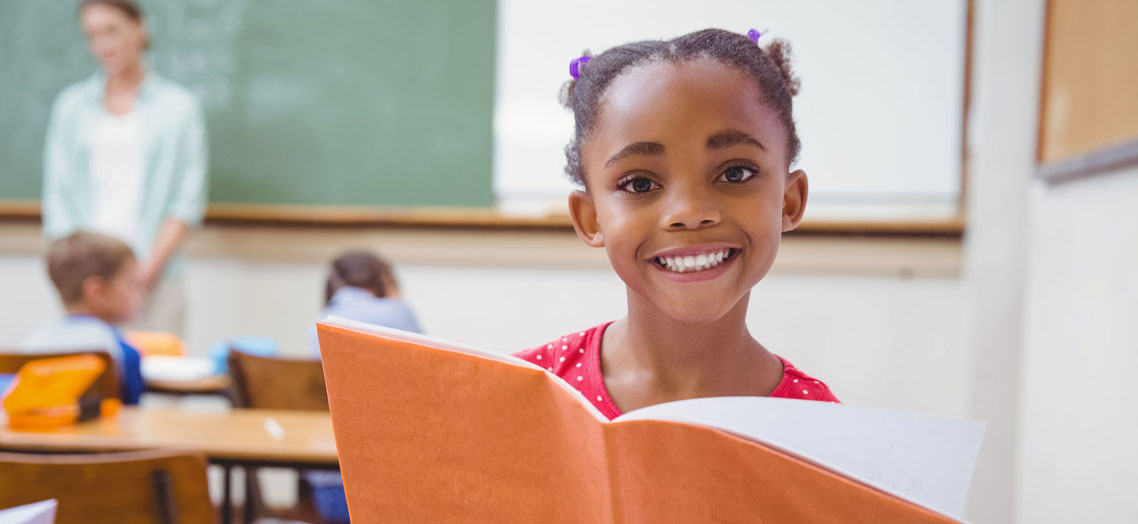 little girl holding a book smiling