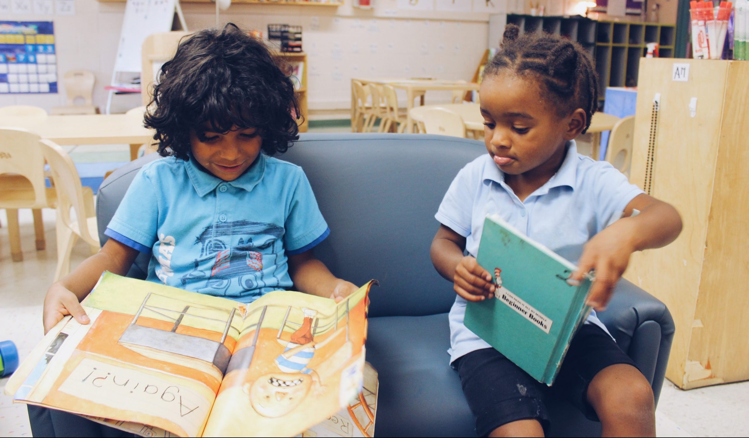 young children seated on a sofa with books